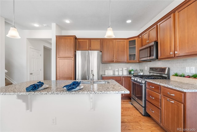 14892 E Poundstone Dr, Aurora, CO 80015 - kitchen featuring appliances with stainless steel finishes, brown cabinetry, a breakfast bar, glass insert cabinets, and backsplash