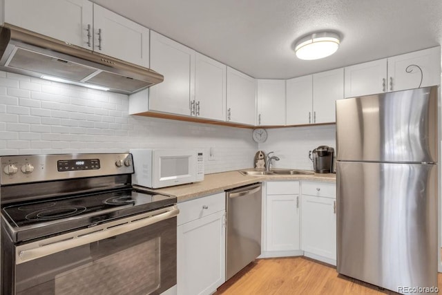 kitchen with light wood-type flooring, appliances with stainless steel finishes, white cabinetry, and sink