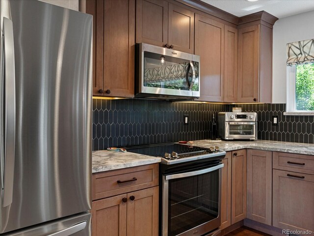 7554 S Ogden Way, Centennial, CO 80122 - kitchen featuring stainless steel appliances, decorative backsplash, and light stone countertops
