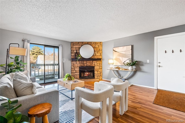 living room featuring a textured ceiling, a stone fireplace, and hardwood / wood-style flooring