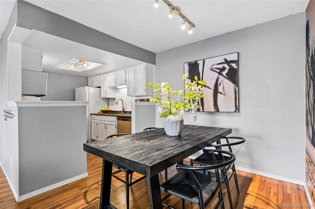 dining room featuring a textured ceiling, light hardwood / wood-style floors, and sink