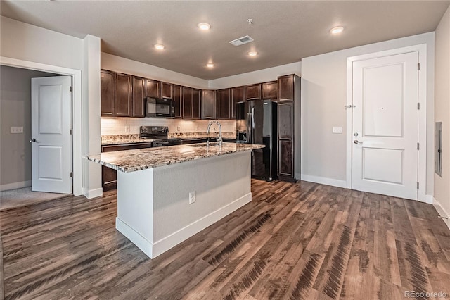 kitchen with black appliances, dark brown cabinets, sink, and a kitchen island with sink