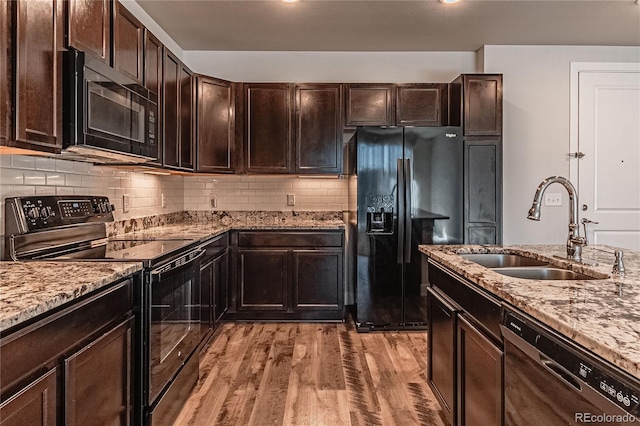 kitchen featuring dark brown cabinetry, light hardwood / wood-style flooring, black appliances, and sink