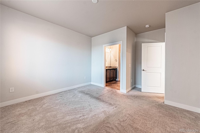 unfurnished bedroom with ensuite bath and light colored carpet