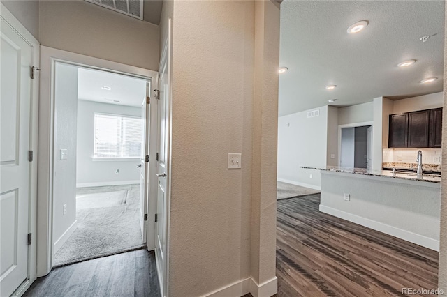 corridor with dark wood-type flooring and sink