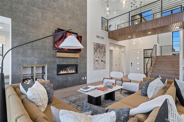 living room featuring tile walls, a towering ceiling, a fireplace, and wood-type flooring