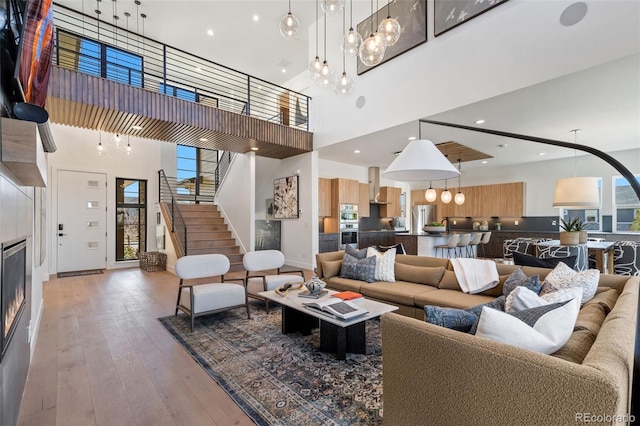 living room with a towering ceiling, wood-type flooring, a tile fireplace, and a healthy amount of sunlight