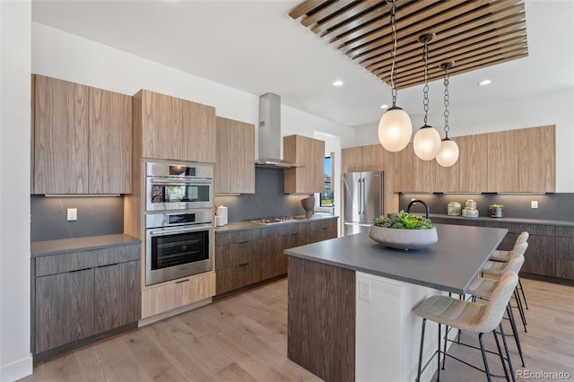 kitchen with a center island, appliances with stainless steel finishes, pendant lighting, range hood, and decorative backsplash