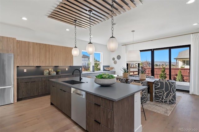 kitchen featuring sink, decorative light fixtures, a kitchen breakfast bar, stainless steel fridge, and dishwasher