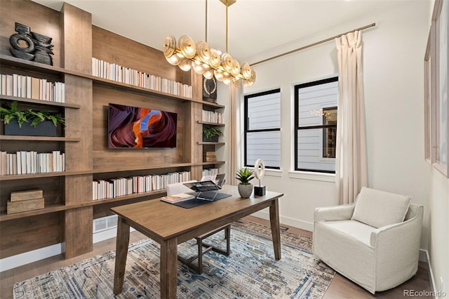 office featuring hardwood / wood-style floors, an inviting chandelier, and built in shelves