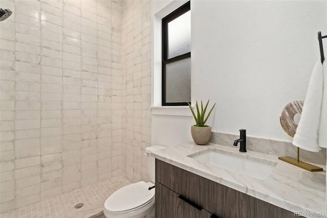 bathroom featuring tiled shower, vanity, and toilet