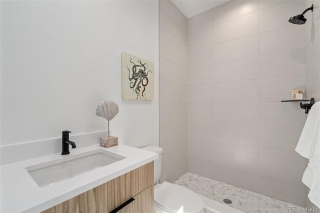 bathroom with vanity, toilet, and tiled shower