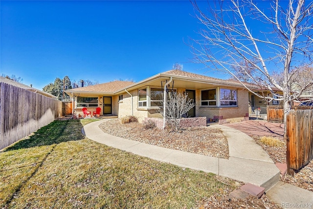 ranch-style house with a fenced backyard, brick siding, and a front lawn