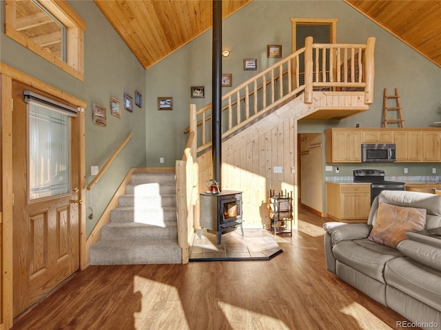 living room with high vaulted ceiling, wooden ceiling, light hardwood / wood-style floors, and a wood stove