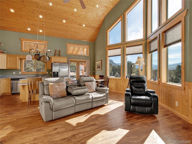 living room featuring high vaulted ceiling, wooden walls, wooden ceiling, and light wood-type flooring