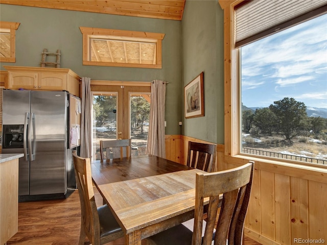 dining area featuring wood walls, light wood-type flooring, and french doors