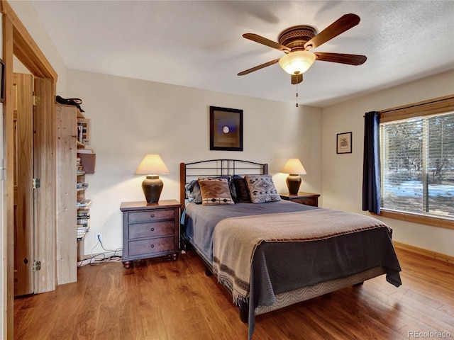 bedroom featuring ceiling fan, hardwood / wood-style floors, and a textured ceiling