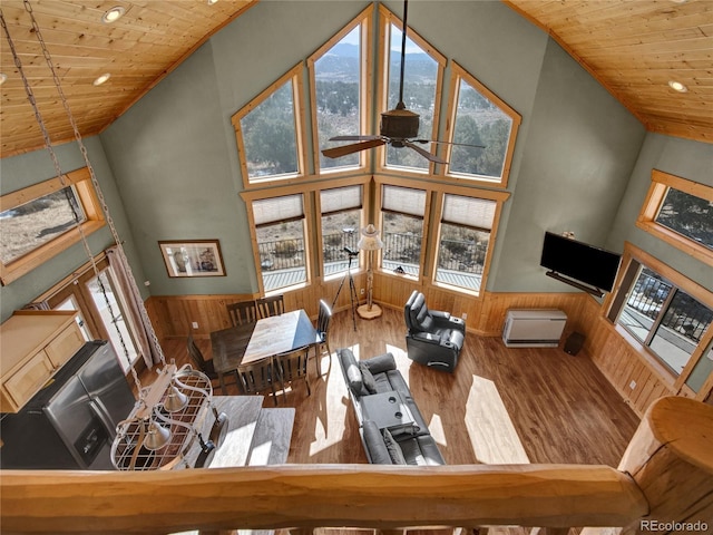 living room with wooden ceiling, high vaulted ceiling, and wood walls