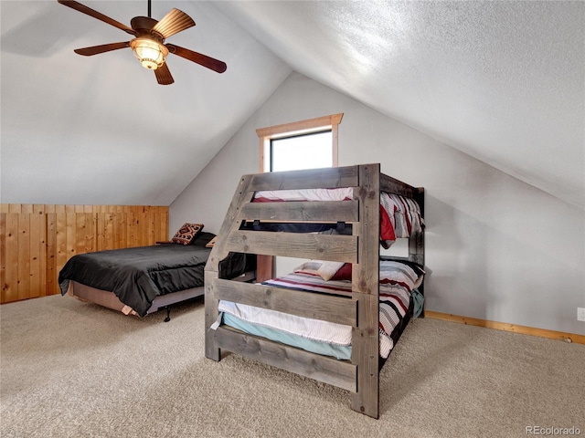 bedroom featuring light carpet, vaulted ceiling, ceiling fan, and wood walls