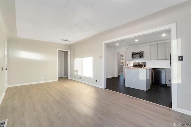 kitchen with appliances with stainless steel finishes, wood counters, and hardwood / wood-style floors