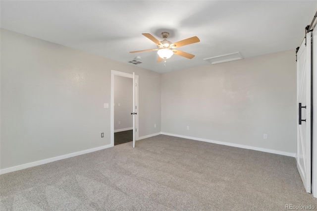 carpeted spare room with ceiling fan and a barn door