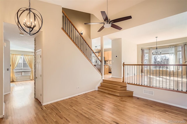 interior space with visible vents, a towering ceiling, baseboards, and wood finished floors