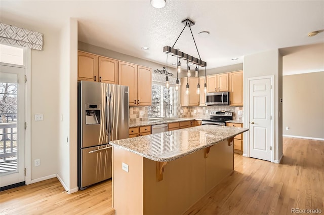 kitchen with a center island, decorative backsplash, light brown cabinetry, appliances with stainless steel finishes, and light wood-type flooring