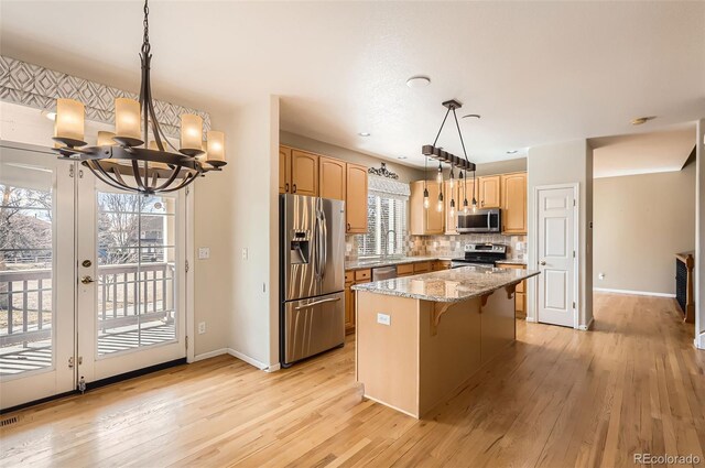 kitchen with light wood-style flooring, decorative backsplash, appliances with stainless steel finishes, light brown cabinets, and a kitchen island