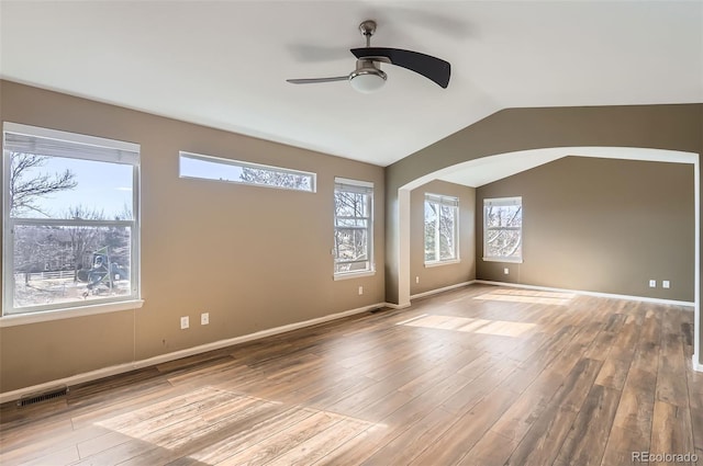 spare room with lofted ceiling, visible vents, baseboards, and wood finished floors