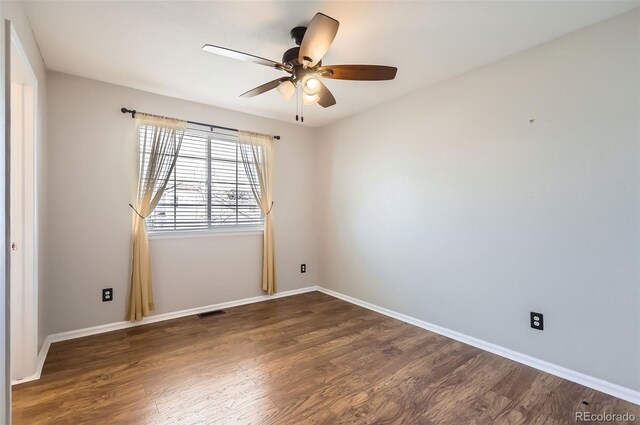 empty room featuring a ceiling fan, visible vents, baseboards, and wood finished floors