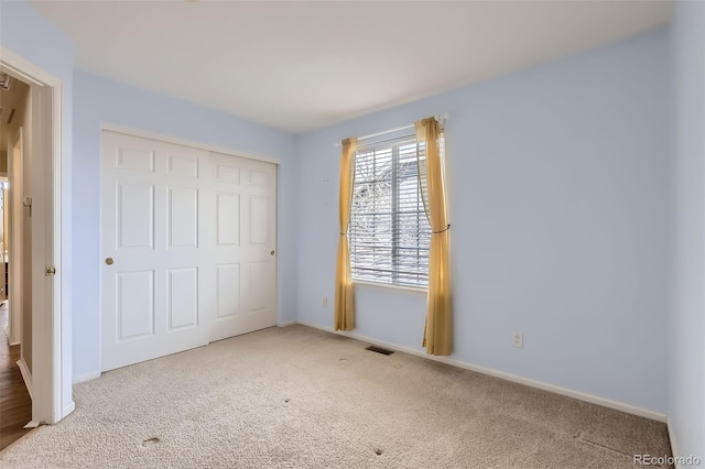 unfurnished bedroom featuring a closet, carpet, visible vents, and baseboards