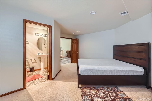 bedroom with light carpet, visible vents, baseboards, ensuite bath, and a sink