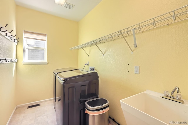 washroom featuring laundry area, baseboards, visible vents, separate washer and dryer, and a sink