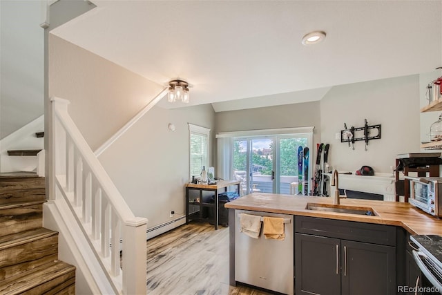 kitchen with sink, butcher block countertops, vaulted ceiling, a baseboard radiator, and dishwasher