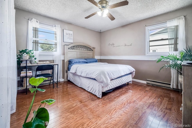 bedroom with multiple windows, a textured ceiling, ceiling fan, and hardwood / wood-style flooring