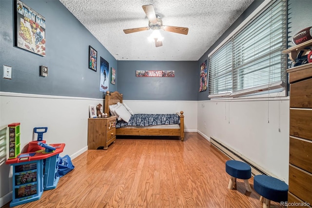 bedroom featuring ceiling fan, baseboards, a textured ceiling, and wood finished floors