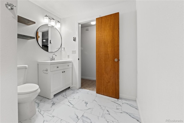 bathroom with toilet, marble finish floor, baseboards, and vanity