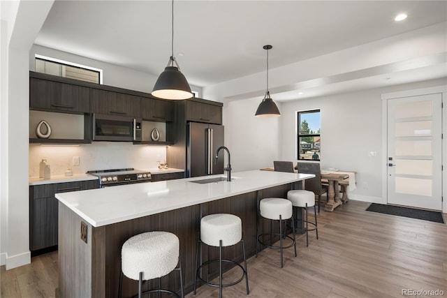 kitchen featuring sink, a center island with sink, decorative light fixtures, and appliances with stainless steel finishes