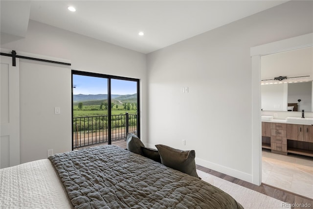 bedroom featuring sink, a barn door, a mountain view, ensuite bathroom, and access to outside