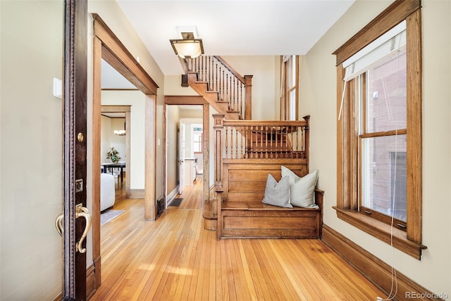 entrance foyer with light wood-style floors, baseboards, and stairway