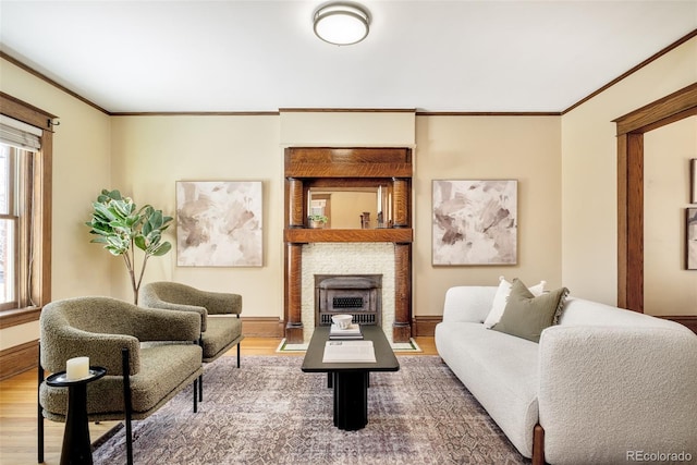 living area featuring baseboards, a large fireplace, wood finished floors, and crown molding