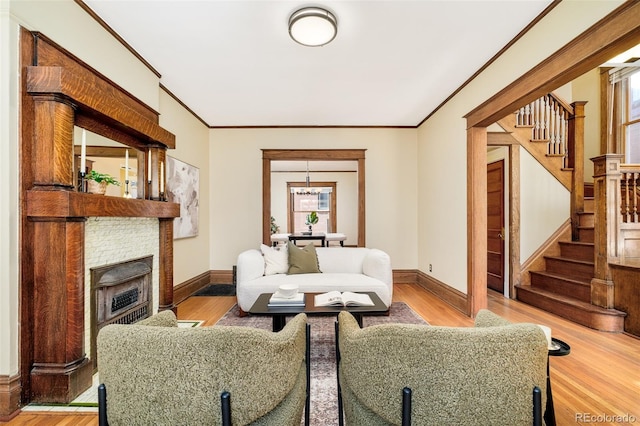 living room featuring stairs, ornamental molding, a fireplace, and wood finished floors