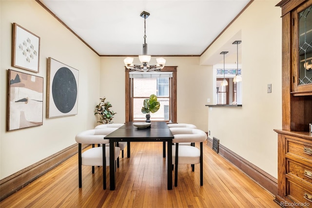 dining space with an inviting chandelier, baseboards, light wood finished floors, and crown molding