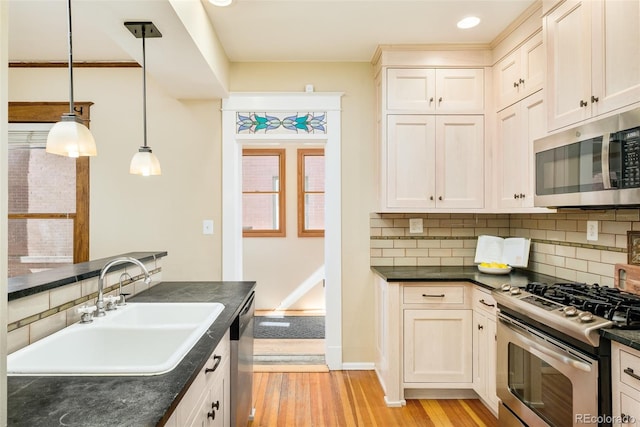 kitchen with stainless steel appliances, dark countertops, and a sink