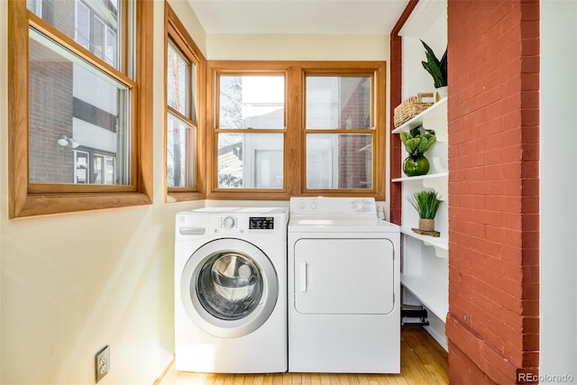 clothes washing area with light wood-style floors, laundry area, and washing machine and clothes dryer