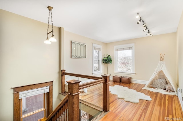 interior space featuring track lighting, baseboards, wood finished floors, and an upstairs landing