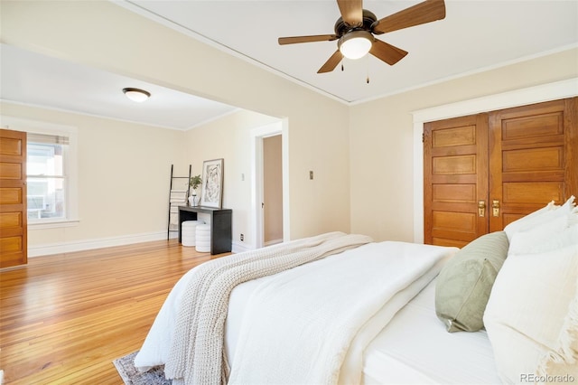 bedroom featuring crown molding, light wood finished floors, a closet, ceiling fan, and baseboards