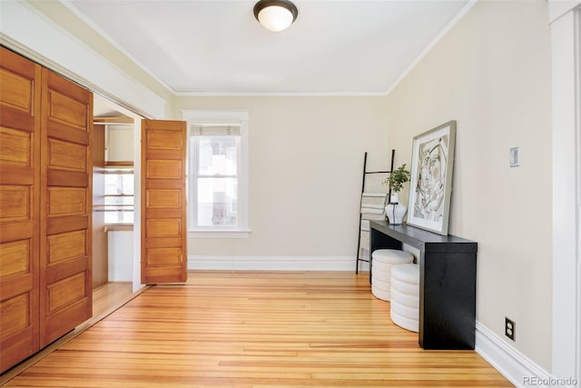 interior space with ornamental molding, baseboards, and light wood finished floors