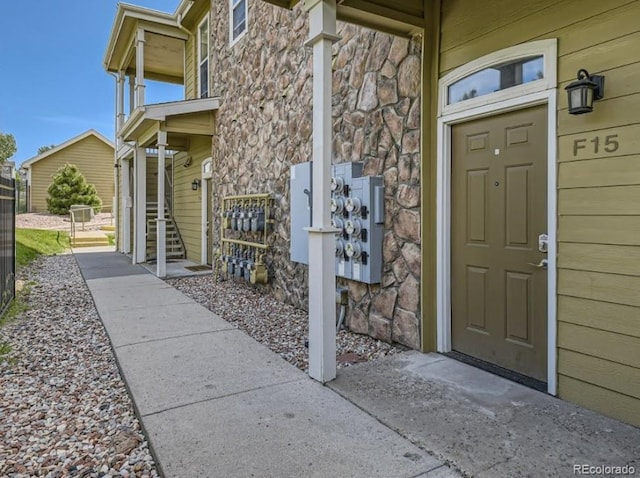 view of exterior entry with fence and stone siding