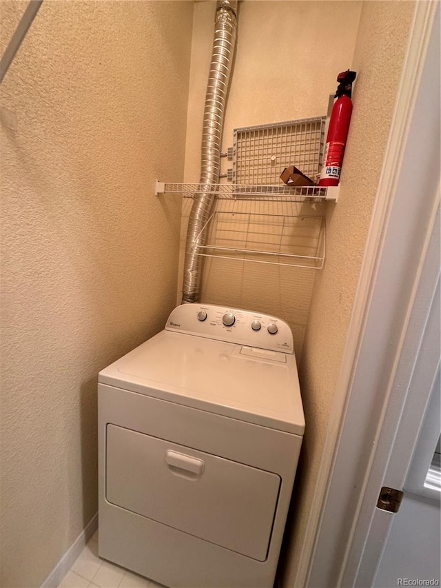 clothes washing area featuring laundry area, washer / dryer, a textured wall, and light tile patterned flooring